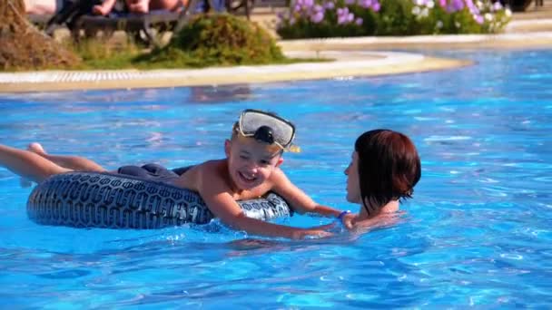 Счастливая семейная мама и маленький сын в круговом плавании в бассейне с голубой водой в отеле. Slow Motion — стоковое видео
