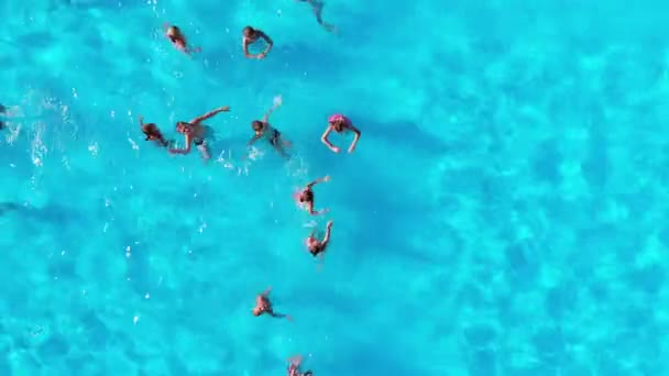 Bovenaanzicht op een zwembad met blauw water en zwemmende kinderen. Wateroppervlaktetextuur — Stockvideo