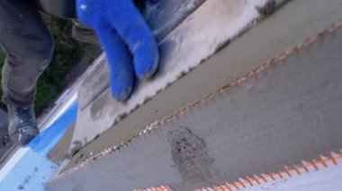 Endüstriyel dağcı, fiberglas örgü üzerinde Trowel macunu yapıştırıcısı kullanarak dış cepheyi izole ediyor.