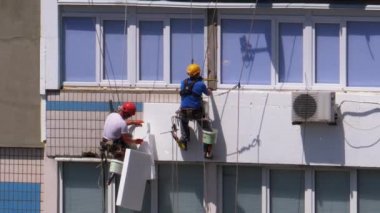 Endüstriyel dağcılık. Binanın köpük yalıtım maskesini kullanan iki tırmanıcı