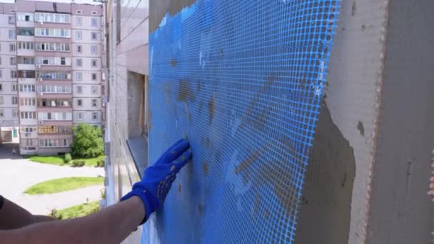 Escalador industrial que usa pegamento de masilla de paleta en malla de fibra de vidrio para aislar la fachada — Vídeos de Stock