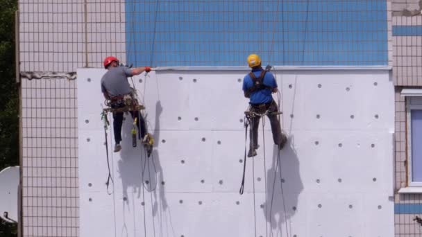 Industrialpinism. Två klättrare använder styrofoam isoleringsfasad av byggnaden — Stockvideo