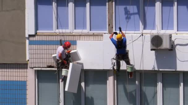 Индустриальный альпинизм. Два альпиниста используют изоляционный фасад здания из пенопласта — стоковое видео