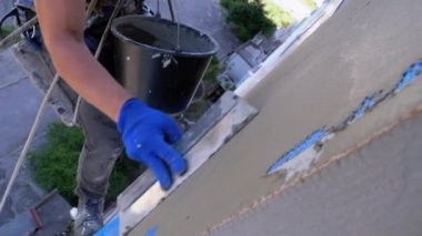 Endüstriyel dağcı, fiberglas örgü üzerinde Trowel macunu yapıştırıcısı kullanarak dış cepheyi izole ediyor.