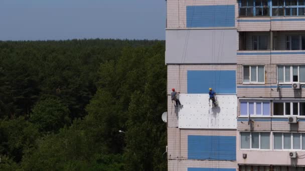 Dos escalador industrial, fachada de aislamiento de edificio de gran altura utilizando espuma de poliestireno — Vídeo de stock