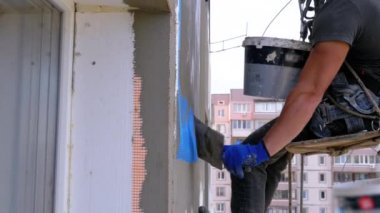 Endüstriyel dağcı, fiberglas örgü üzerinde Trowel macunu yapıştırıcısı kullanarak dış cepheyi izole ediyor.