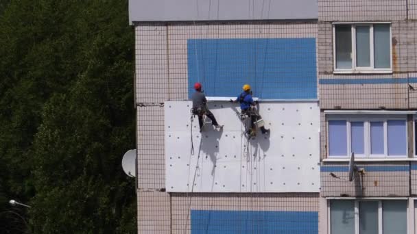 Два промышленных альпиниста, изоляционный фасад высотного здания с использованием пенопласта — стоковое видео