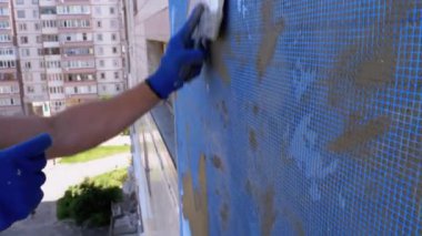 Endüstriyel dağcı, fiberglas örgü üzerinde Trowel macunu yapıştırıcısı kullanarak dış cepheyi izole ediyor.
