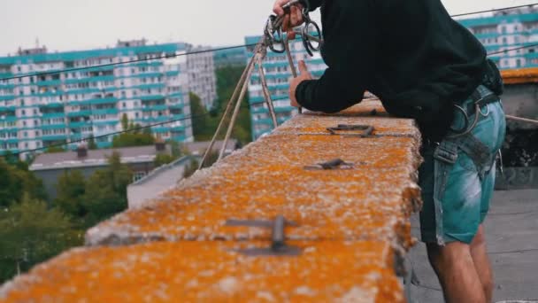 Escalador industrial en equipo al borde del tejado se prepara para caer en las cuerdas — Vídeo de stock