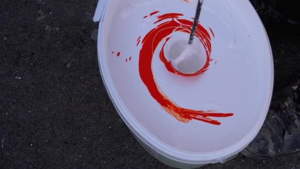 Het mengen van wit met rode verf in de emmer met behulp van Whisk op een boor. Langzame beweging — Stockvideo