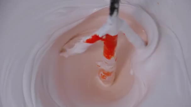 Mélanger du blanc avec de la peinture rouge dans le seau à l'aide d'un fouet sur une perceuse. Mouvement lent — Video