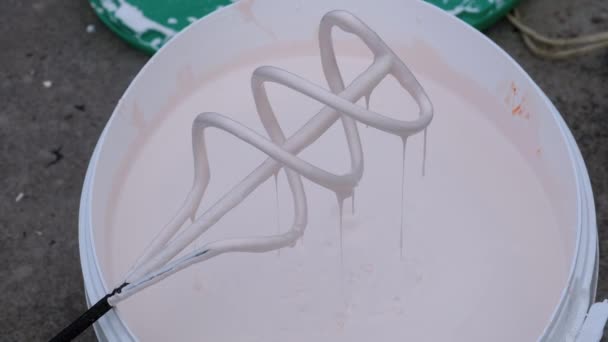 Drops of White Paint Drip in Bucket from Whisk on Construction Site. Slow Motion — Stock Video