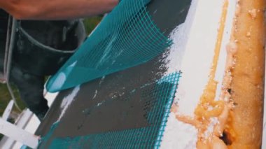 Endüstriyel dağcı, fiberglas örgü üzerinde Trowel macunu yapıştırıcısı kullanarak dış cepheyi izole ediyor.