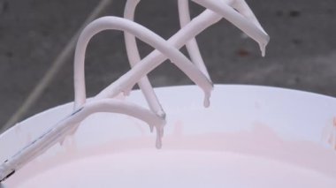 Whisk on İnşaat Alanından Kova içinde Beyaz Boya Damlaları. Yavaş Hareket