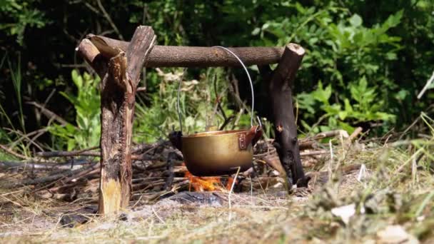 Cocinar en un fuego abierto en una olla turística. Turista Bowler sombrero colgando en hoguera — Vídeos de Stock