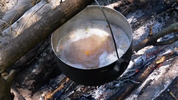 在旅游景点的篝火上做饭。观光客鲍勒帽子挂在篝火旁 — 图库视频影像