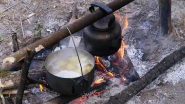 Turist mekanında ateşte yemek pişirmek. Turist Bowlingci Şapka Şenlik Ateşi 'nde Asılı