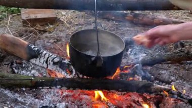 Turist mekanında ateşte yemek pişirmek. Turist Bowlingci Şapka Şenlik Ateşi 'nde Asılı