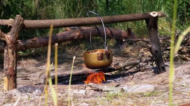 在旅游景点的篝火上做饭。观光客鲍勒帽子挂在篝火旁 — 图库视频影像