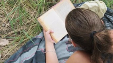 Genç Kadın, Yaz Gününde Doğanın Çimlerinde Yatan Bir Kitap Okuyor.
