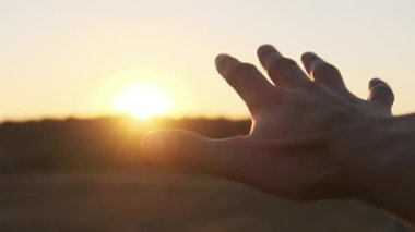 Erkek El Sunset 'e karşı. Güneşe dokun. Güneş parmaklarıyla parlar. Yavaş çekim
