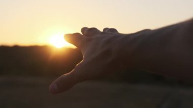 Erkek El Sunset 'e karşı. Güneşe dokun. Güneş parmaklarıyla parlar. Yavaş çekim