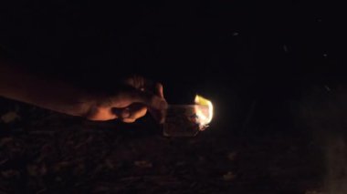 Doğa 'da Kamp Ateşi' nin yakınındaki Kara Arkaplanda El Yakma Kartı. Yavaş çekim