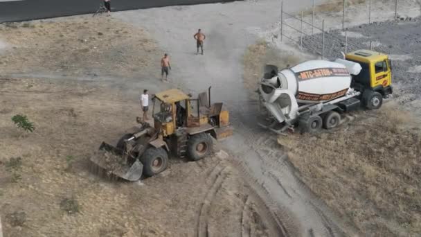 Planierraupe zieht auf einer Baustelle einen Betonmischer aus dem Sand — Stockvideo