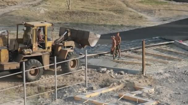 Buldożer wylewa płynny beton z wiadra na ziemię. Plac budowy — Wideo stockowe