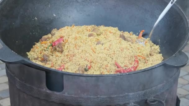 Großer Bottich mit gekochtem Pilaf oder Reis über offenem Feuer. Street Food auf der Party — Stockvideo