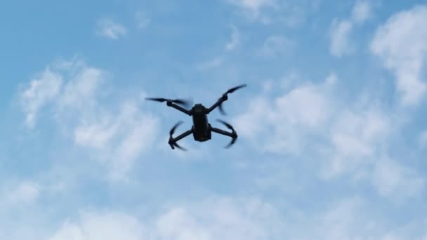 Drone pende in aria contro il cielo blu, Vista dal basso. Rallentatore — Video Stock