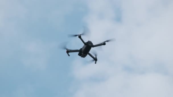 Dronen henger i luften mot Den blå himmelen, sett nedenfra. Langsom bevegelse – stockvideo
