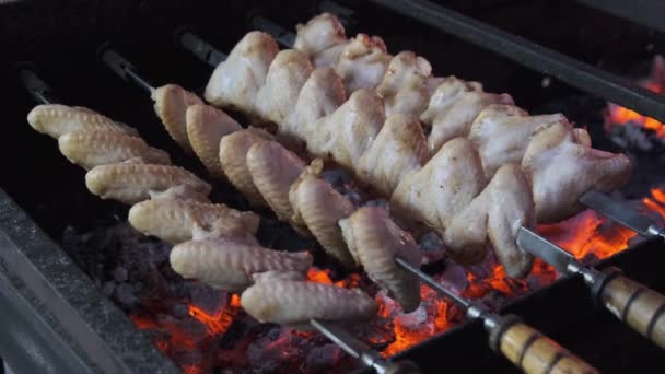 Asas de frango em espetos é cozido em churrasco no Festival de comida de rua — Vídeo de Stock