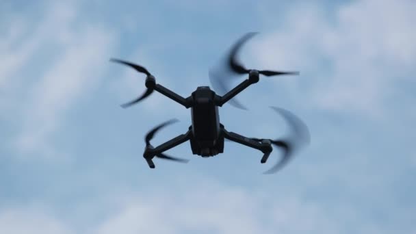 Drone hangt in de lucht tegen de blauwe lucht, Uitzicht van onderen. Langzame beweging — Stockvideo