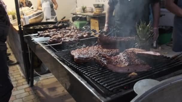 Мясо на гриле на фестивале уличной еды. Большие куски свинины жареные на барбекю — стоковое видео