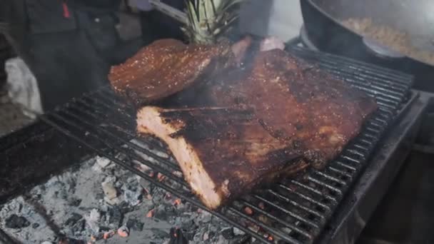 La carne es asada en el Street Food Festival. Grandes trozos de cerdo asado en la barbacoa — Vídeo de stock