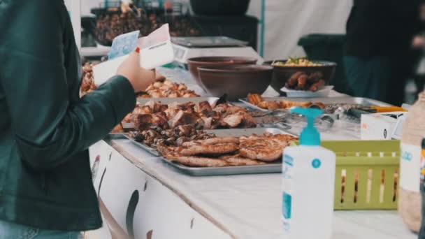 El comprador compra comida a la parrilla y transfiere dinero al vendedor en un festival callejero — Vídeos de Stock