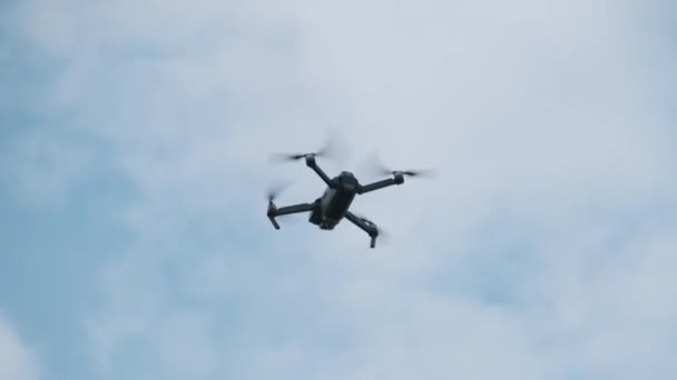 Dronen henger i luften mot Den blå himmelen, sett nedenfra. Langsom bevegelse – stockvideo