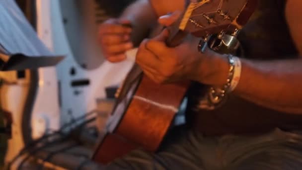 Street gitarrist Spelar akustisk gitarr på natten i ljuset från Campfire. — Stockvideo