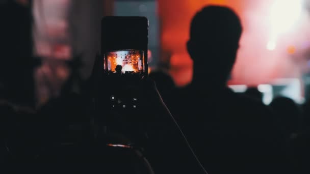 Vrouw handen silhouet opname video van live muziekconcert met smartphone — Stockvideo