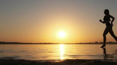 Plaj boyunca Altın Gün batımında Sığ Suyla Koşan Kadın. Slow Motion 240 fps