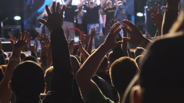 En massa fans på en rockkonsert höjer sina händer. Långsamma rörelser — Stockvideo