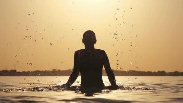 Silueta de Joven Mujer Alegre Salpicando Agua del Río al atardecer. Moción lenta — Vídeos de Stock