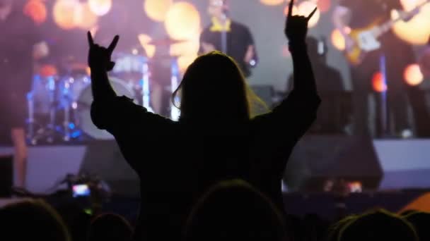 ซิลูเอทของผู้หญิงในฝูงชนที่ร็อคคอนเสิร์ตแสดงป้ายปีศาจฮอร์น — วีดีโอสต็อก
