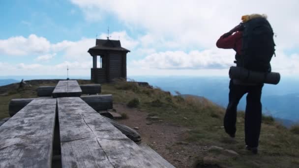 Toerist met rugzak op de top van de berg spreidt zijn armen uit naar de Zijdes — Stockvideo
