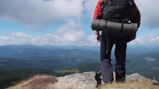 Tourist mit Rucksack auf dem Gipfel des Berges nahe der Klippe hebt die Hände zur Seite — Stockvideo