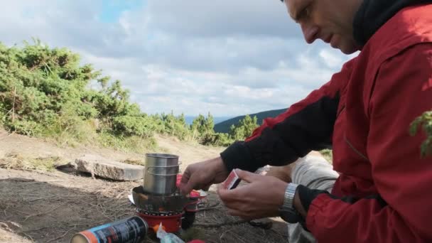 Turysta w górach, przygotowuje herbatę na piecu gazowym. Podróże solo — Wideo stockowe