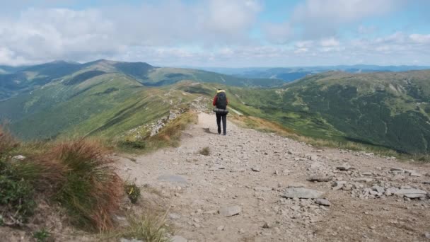 Touriste avec un sac à dos descend le long du sentier de montagne de pierre sur la colline — Video