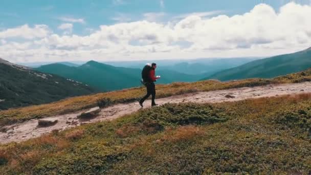 Flybilde av en reisende fotograf med ryggsekk som klatrer forbi fjellkjeden – stockvideo