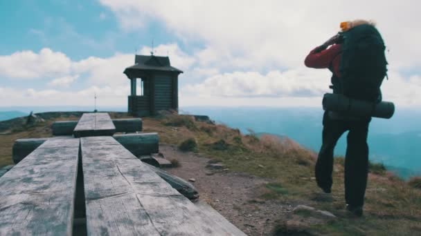 Turista com mochila no topo da montanha espalha seus braços para os lados — Vídeo de Stock